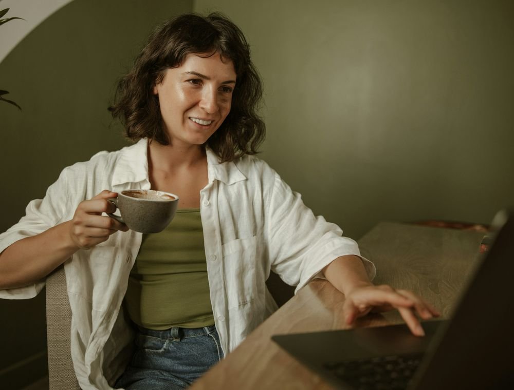 Clinician with a cup of coffee working on her laptop at home, on her own schedule