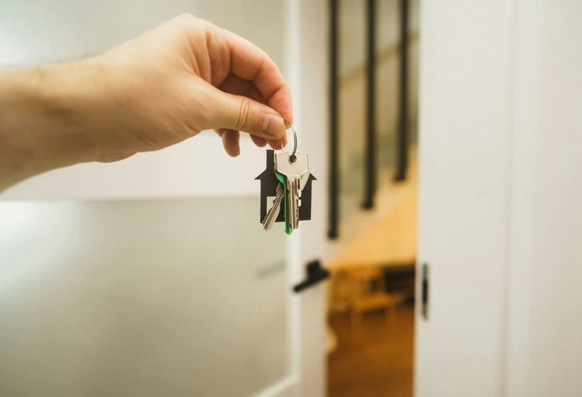 Mano que sostiene las llaves de un apartamento frente a la puerta abierta, después de la aprobación del arrendador